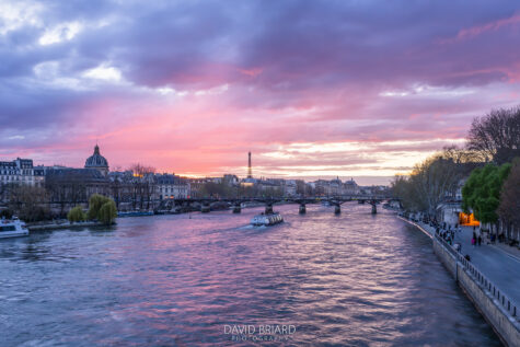 Pink sunset over the Seine river, with a view of the Eiffel Tower and the Pont des Arts in Paris.